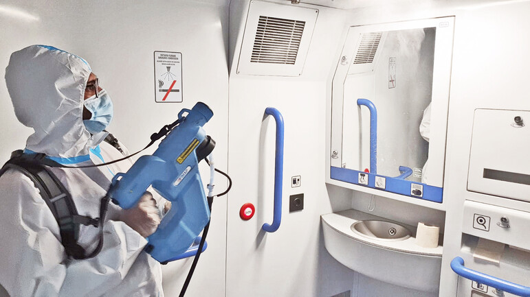 Worker in overalls disinfecting surfaces